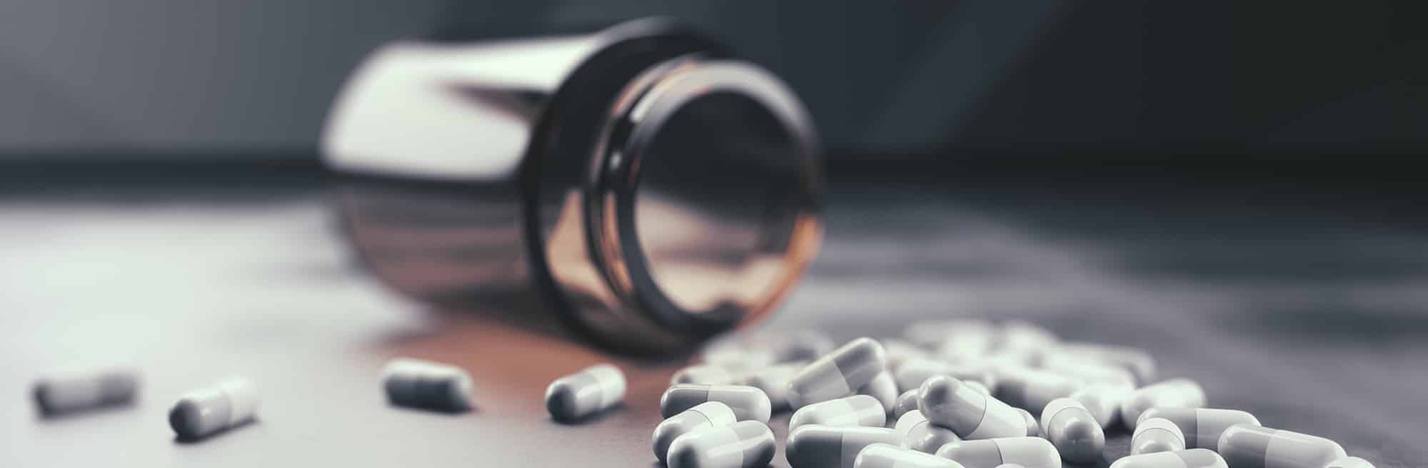 Bottle of prescription pills knocked over with pills scattered on the floor