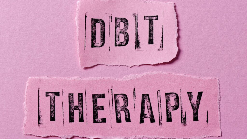 A pink background with the word DBT Therapy is printed in black represents the six main points of dialectical behavior therapy.