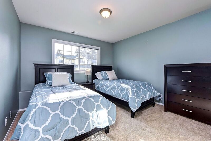 Two twin beds with blue comforters and brown dresser against a window in our rehab for men.