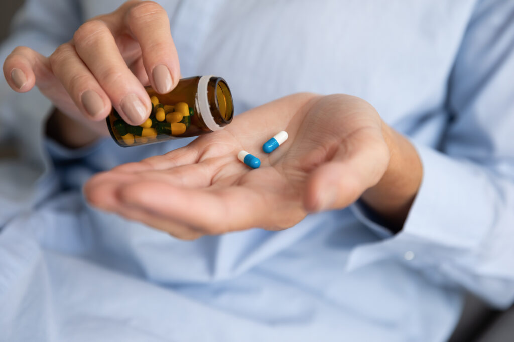 A person is pouring out blue and white pills that represent the arthritis medication meloxicam.