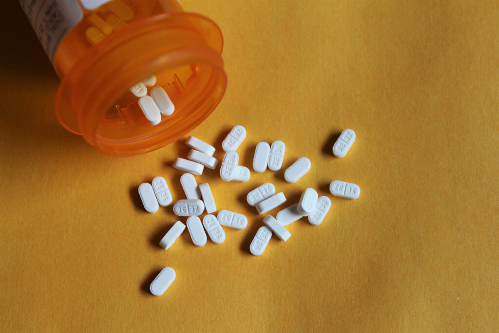 An orange pill bottle of buspirone is spilled over with white tablet scattered on the table representing various dosage of how to taper off buspirone safely.