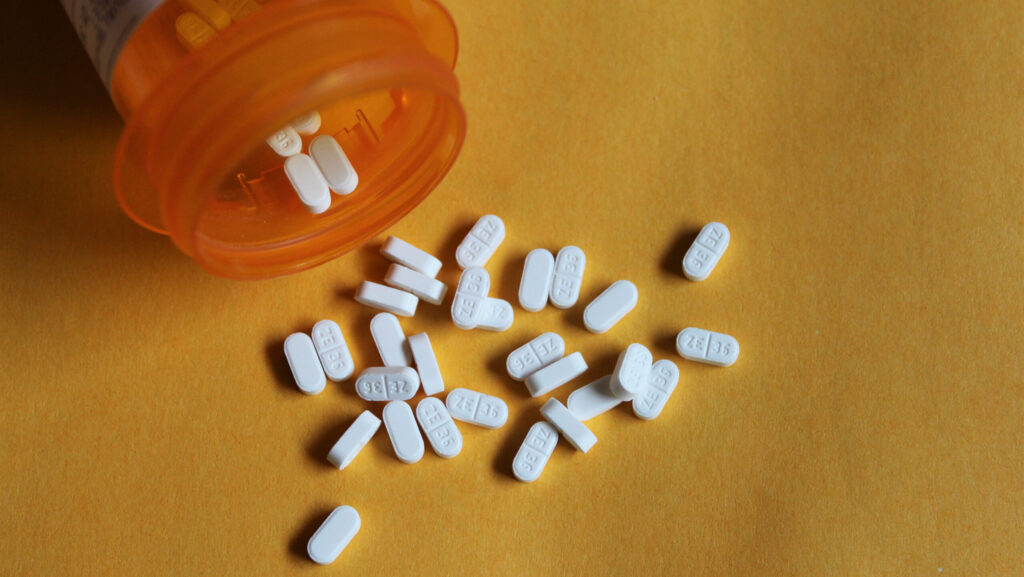 An orange pill bottle of buspirone is spilled over with white tablet scattered on the table representing various dosage of how to taper off buspirone safely.