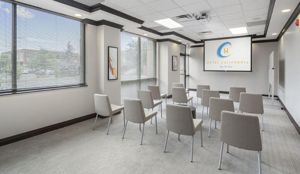 Modern, clean room with Screening of "Hotel California by the Sea" an addiction rehab center near me. Chairs facing screen for viewing. 