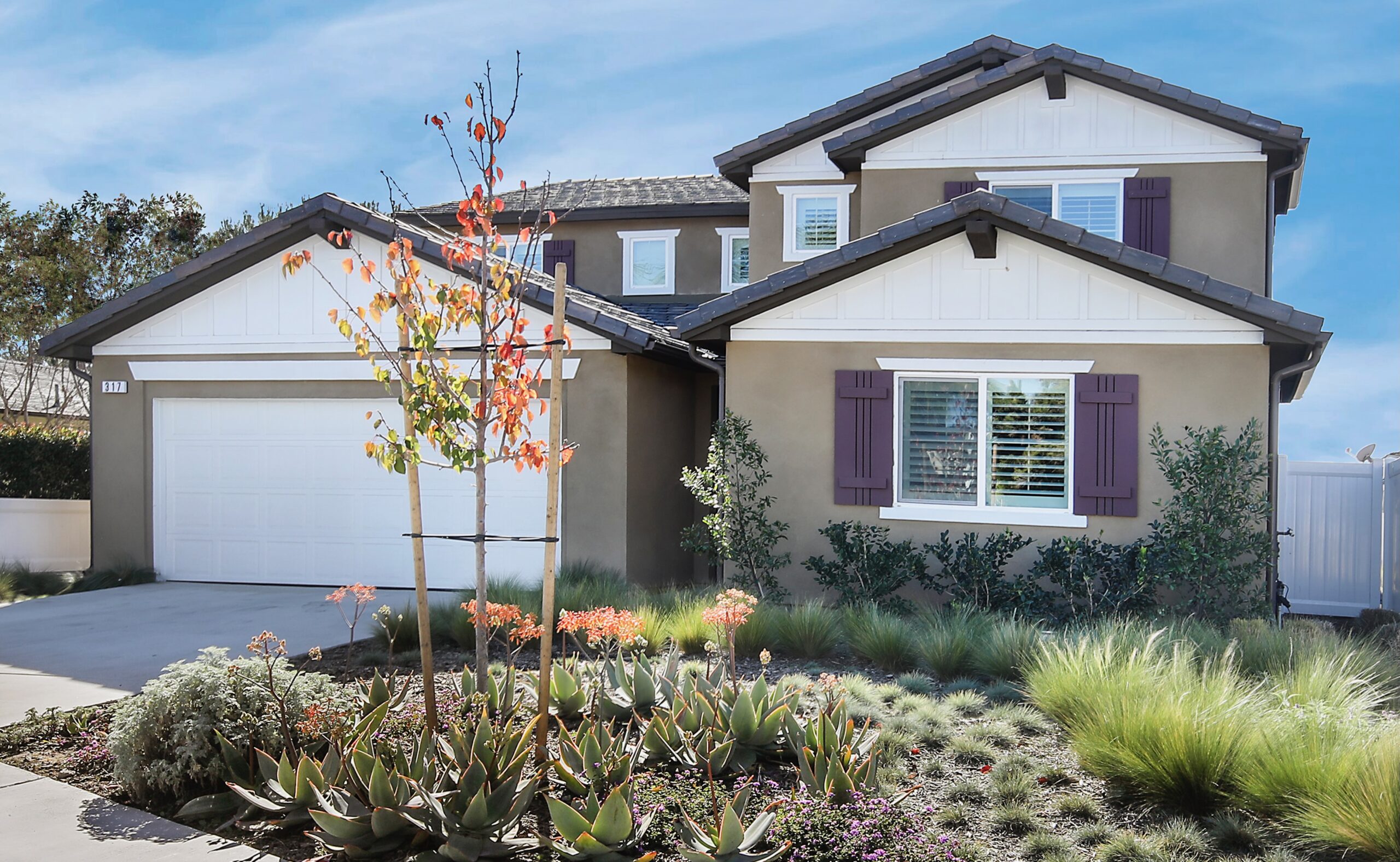 Tan house with white trim and bushes, the front of a Cigna addiction rehab center