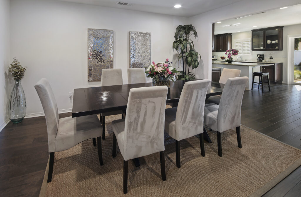 Gray chairs surrounding brown dining room table with flowers.