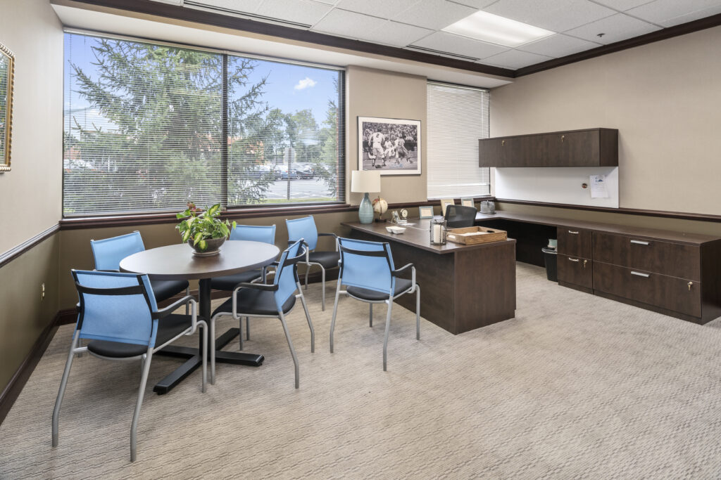 Brown desk with cabinets, blue chairs surrounding brown round table