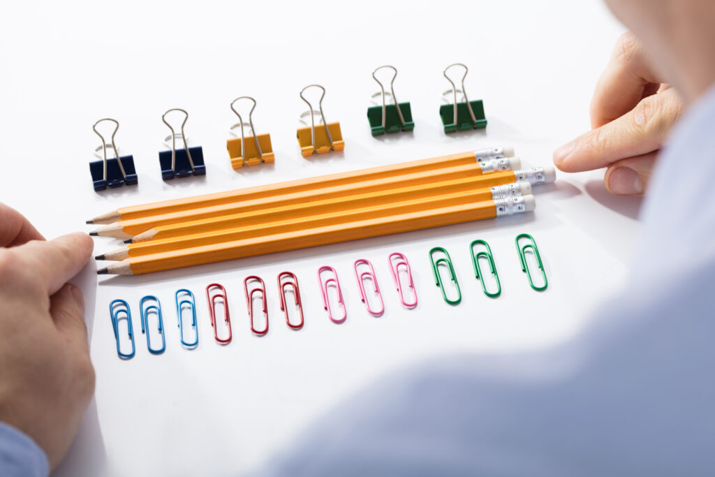 A man organizing paper clips and pencils in neat rows represents characteristics of obsession.