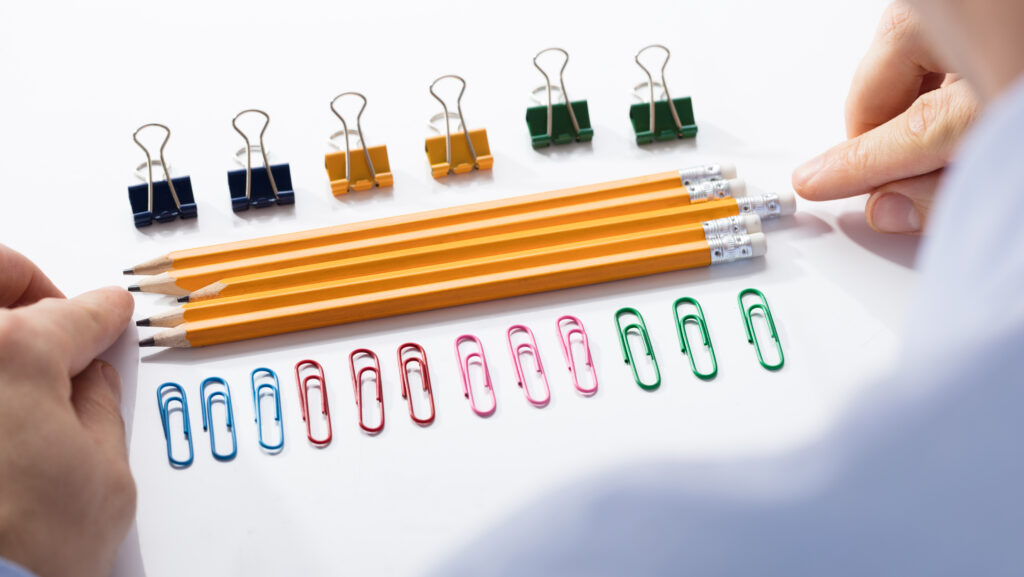 A man organizing paper clips and pencils in neat rows represents characteristics of obsession.