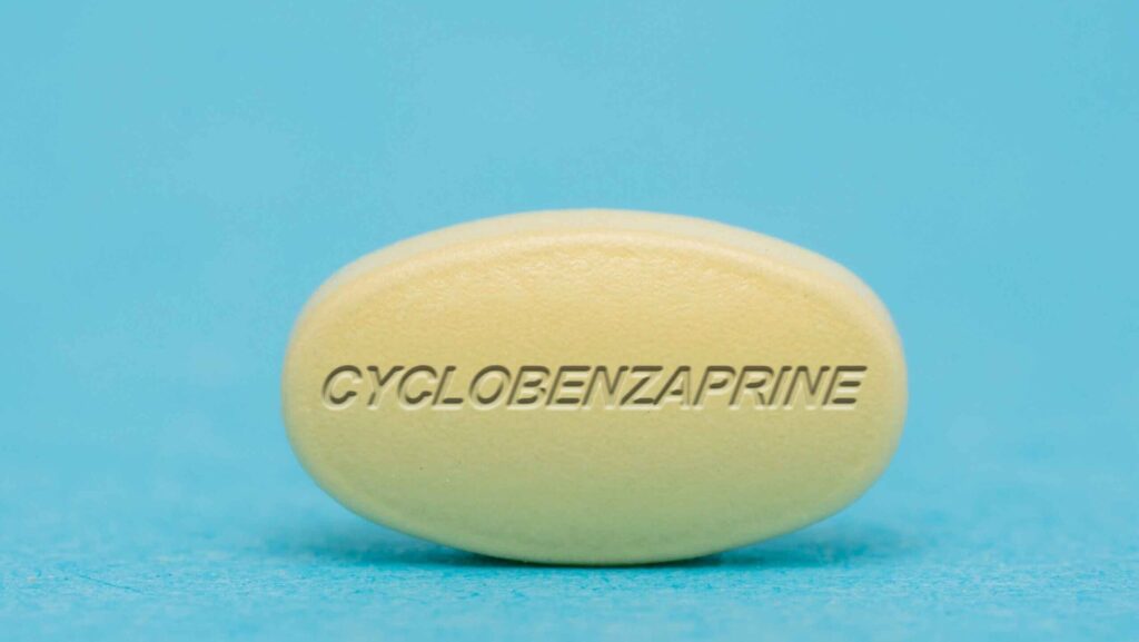 A light colored yellow pill of cyclobenzaprine on a blue background represents cyclobenzaprine withdrawal.