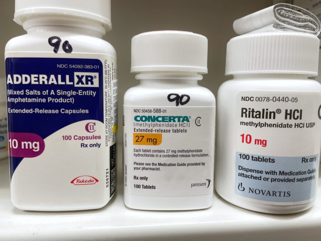 A pill bottle of Adderall, Concerta and Ritalin sitting on a pharmacy shelf represents the possibility of Concerta withdrawal.