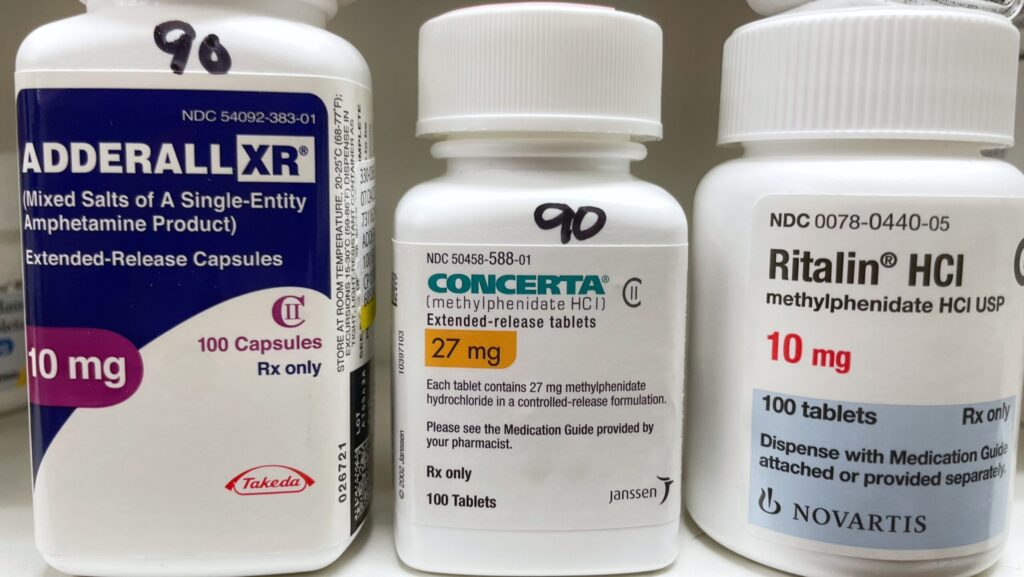 A pill bottle of Adderall, Concerta and Ritalin sitting on a pharmacy shelf represents the possibility of Concerta withdrawal.