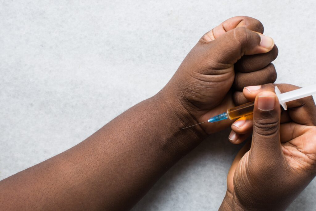 A young person is injecting themselves through a vein on their wrist represents how track marks are formed.