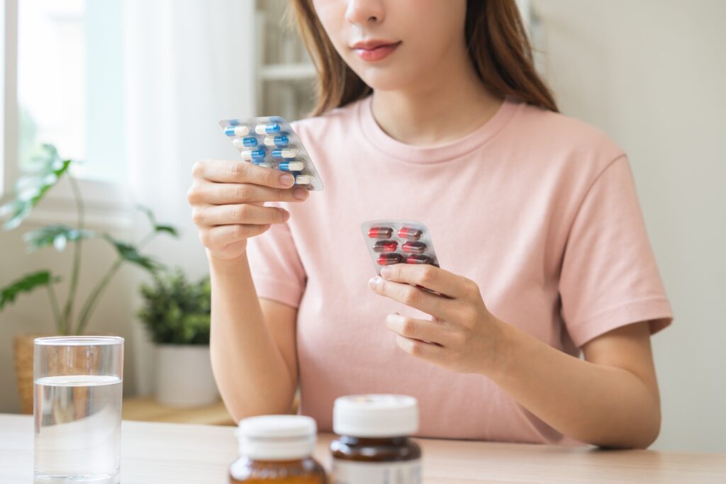 A young women is sitting at a table holding up two different packs of tablets that have resulted in experiencing a paradoxical effect.