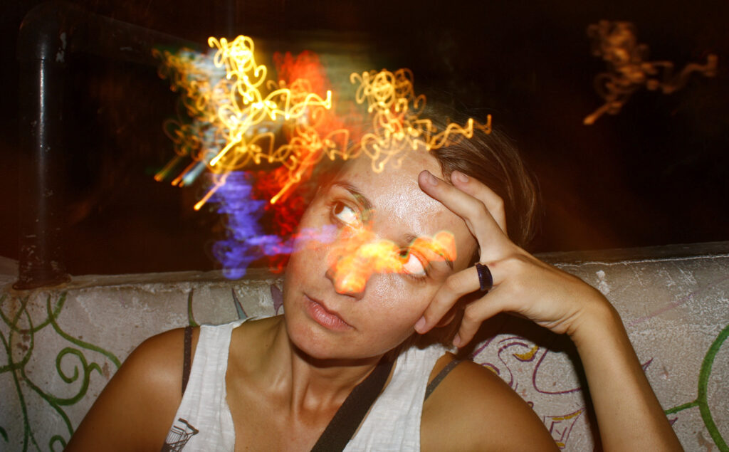 A young women sitting on a sofa experiencing the effects and symptoms of PCP and hallucinating.