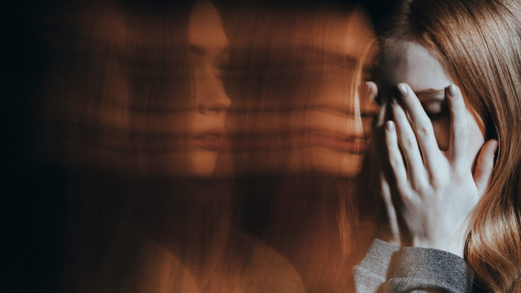 A young women covering her face with her hands experiencing the effects of Adderall and psychosis.