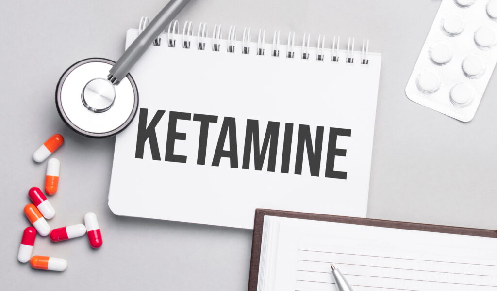 A notebook labeled ketamine sitting on a desk with pills and a stethoscope.