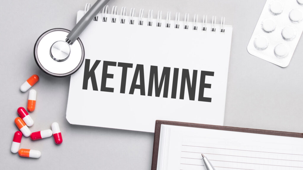 A notebook labeled ketamine sitting on a desk with pills and a stethoscope.