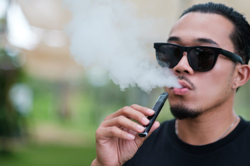 Man with sunglasses vaping and wondering is vaping bad for your teeth.