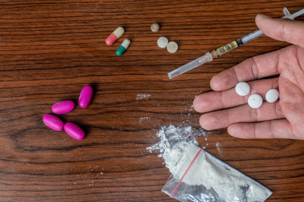 Various narcotic pills, powders and a liquid filled syringe are laid out on a table. Valium is often mistaken for a narcotic.