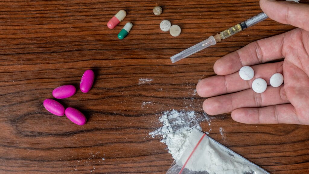 Various narcotic pills, powders and a liquid filled syringe are laid out on a table. Valium is often mistaken for a narcotic.