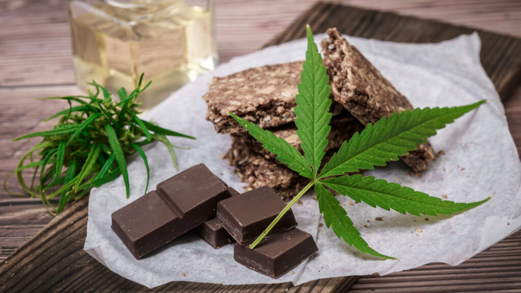 THC infused chocolates and snack bars lay next to cannabis leaves represent the possibility if overdosing on weed.