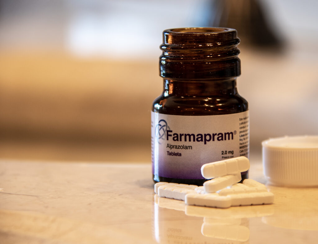 A small pharmacy bottle of Farmapram with tablets laid out next to the bottle on a table.