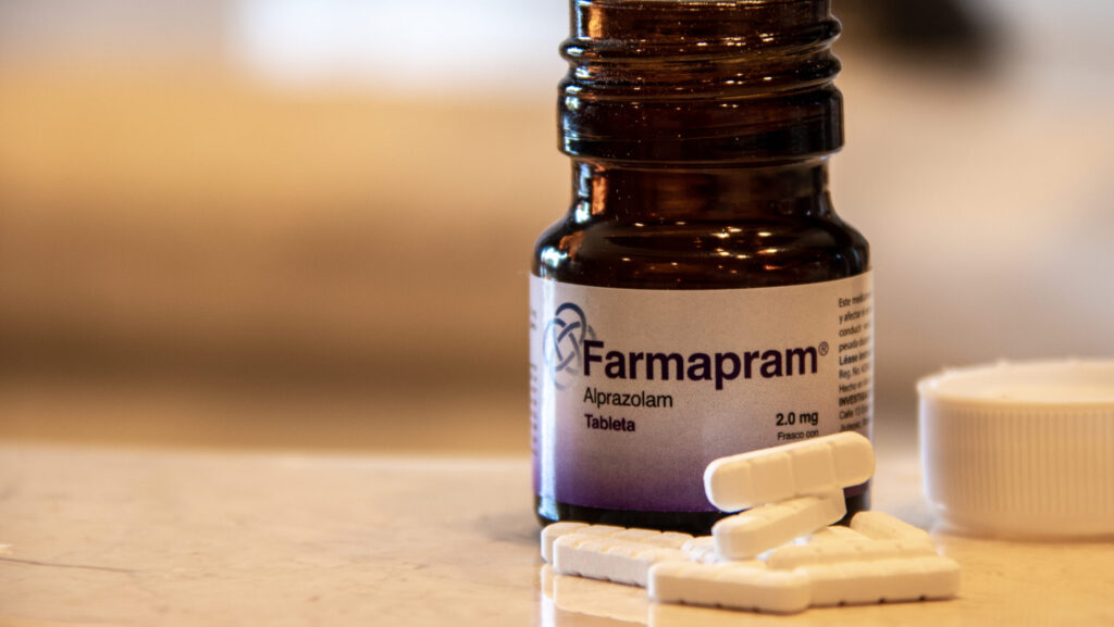 A small pharmacy bottle of Farmapram with tablets laid out next to the bottle on a table.