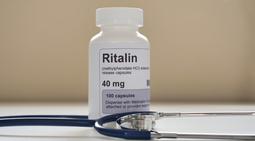 A prescription bottle of Ritalin next to a stethoscope represents the symptoms Ritalin withdrawal.