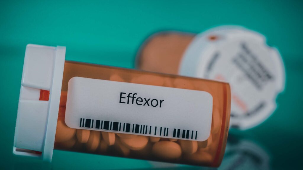 An orange bottle of prescription Effexor laying on the table.