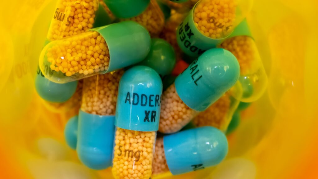 Inside an orange pharmacy medication bottle of Adderall XR capsules that can lead to Adderall overdose effects.