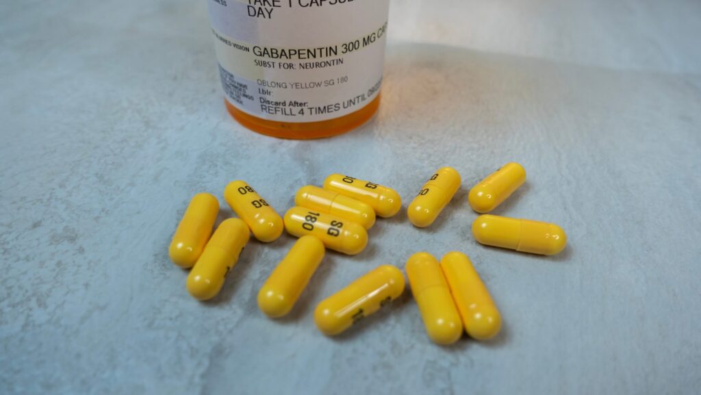 Yellow gabapentin pills next to a pharmacy bottle represents how to get off gabapentin safely.