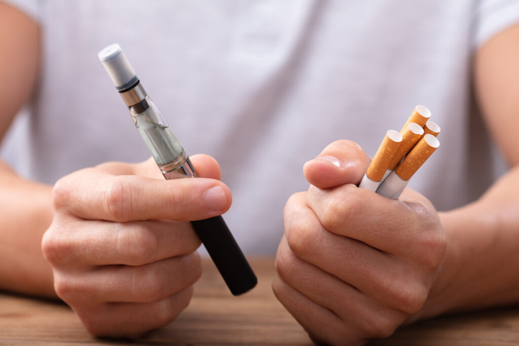 A man hold a vape in in one hand and cigarettes in the other wonders how long it takes to get addicted to nicotine?